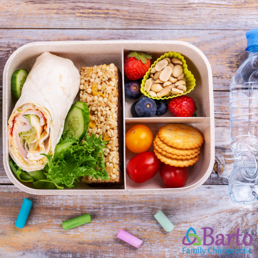 Packed lunch for boy athletes featuring a protein wrap, fruit, veggies, and an energy-boosting nuts for sustained energy during school and sports.